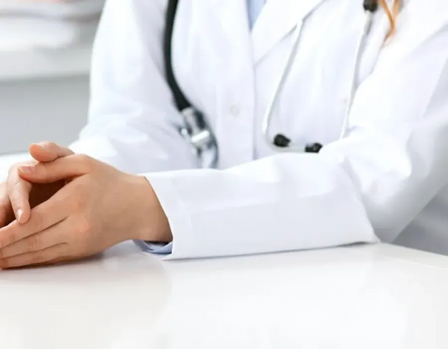 Healthcare manager with hands rested on desk speaking to team during meeting